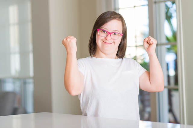 Down syndrome woman at home very excited, cheering emotion