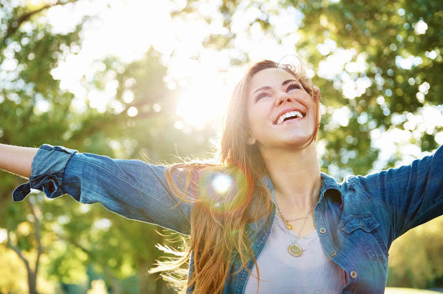 A young woman standing outdoors with her arms outstretched