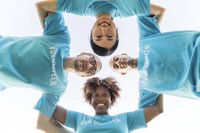 Four volunteers smiling in matching blue t-shirts, viewed from below.